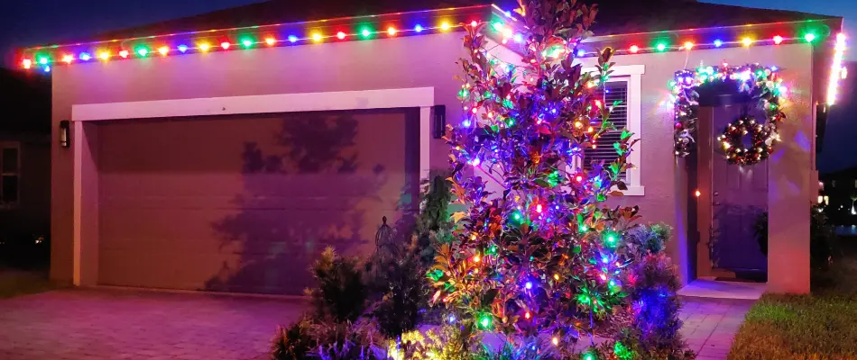 A home in New Smyrna Beach, FL, decorated in colorful commercial-grade Christmas lights with a tree and wreath.