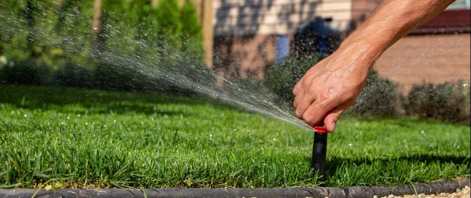 A sprinkler irrigation system in New Smyrna Beach, FL, with a hand trying to repair it.